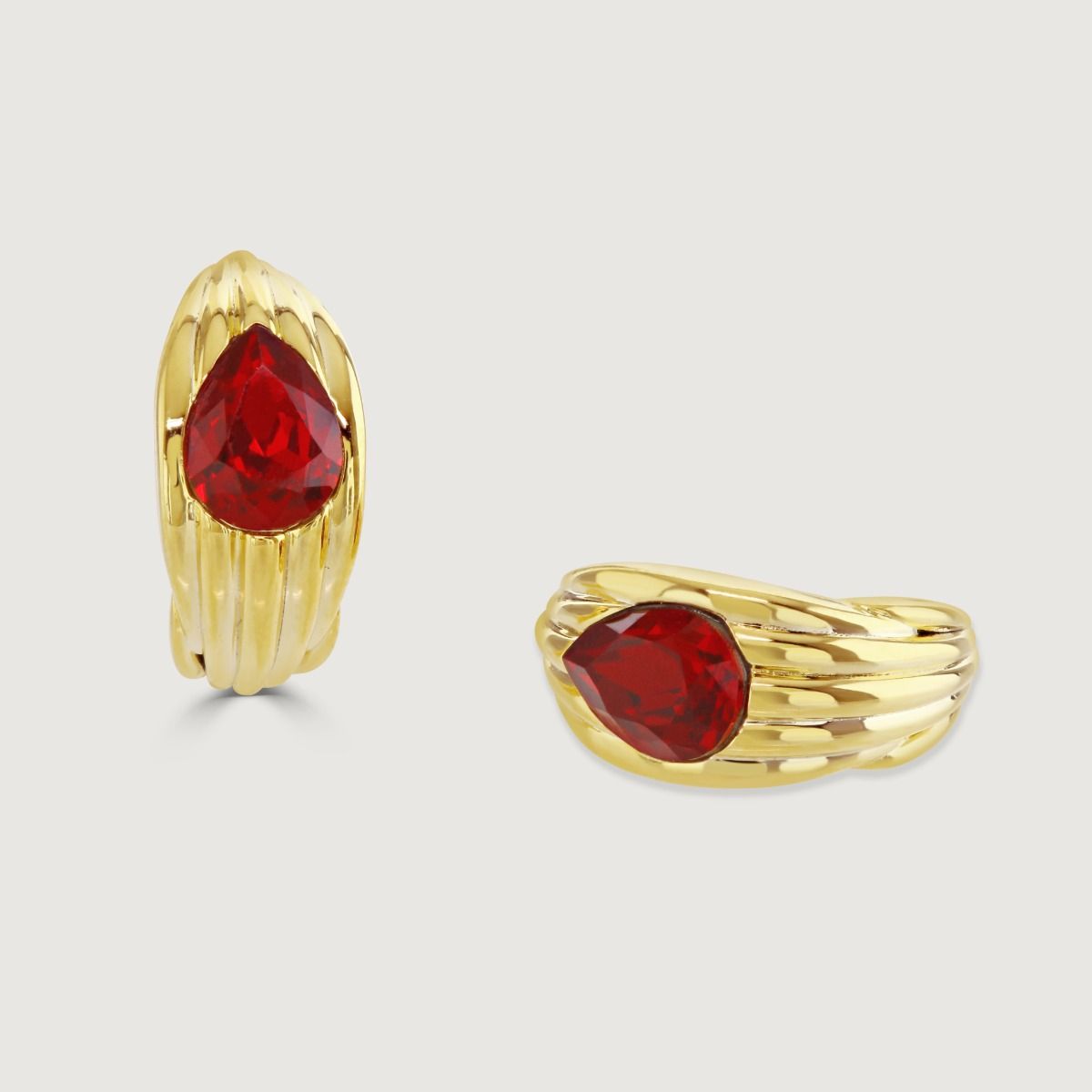 The Praline Huggie Earring ingeniously imitates the praline's texture through debossed vertical scoring. Its cocooned huggie design encases a teardrop stone at the centre, adding a burst of vivid colour. 