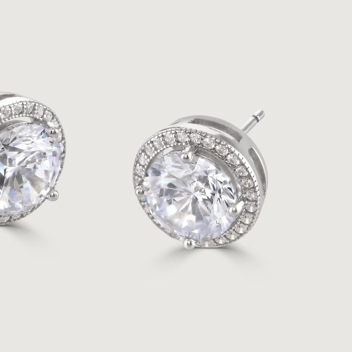 These dazzling stud earrings are set with a halo of flawlessly cut cubic zirconia stones, surrounding a dazzling round clear centre stone for a diamond inspired look. Wear to add timeless glamour to any look.