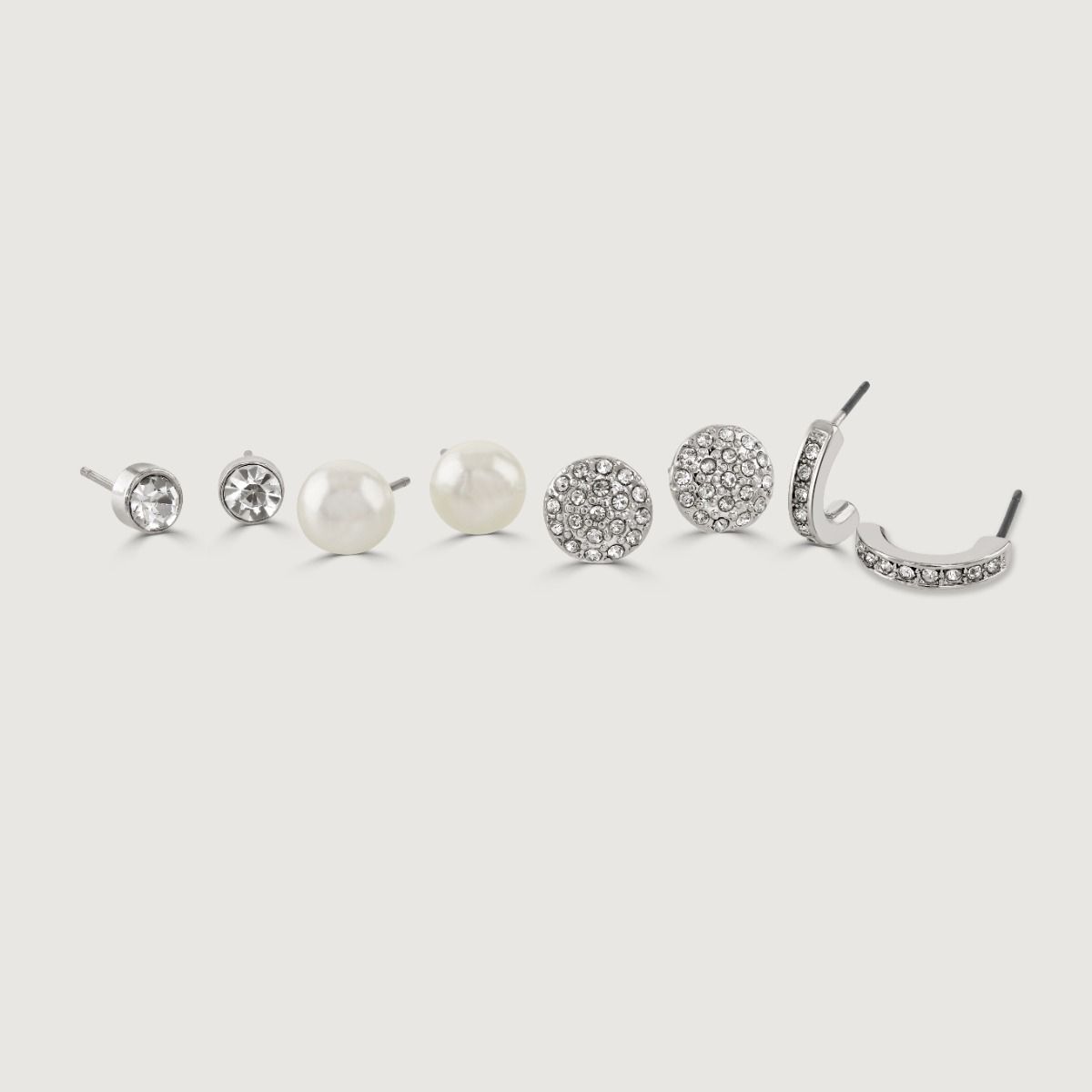 Upgrade your earring collection with this dazzling Rhodium Four Piece Pack. It features a mix of timeless elegance and contemporary flair, including pearl studs for a touch of sophistication, chic hoop earrings for a trendy look, and sparkling crystal ear