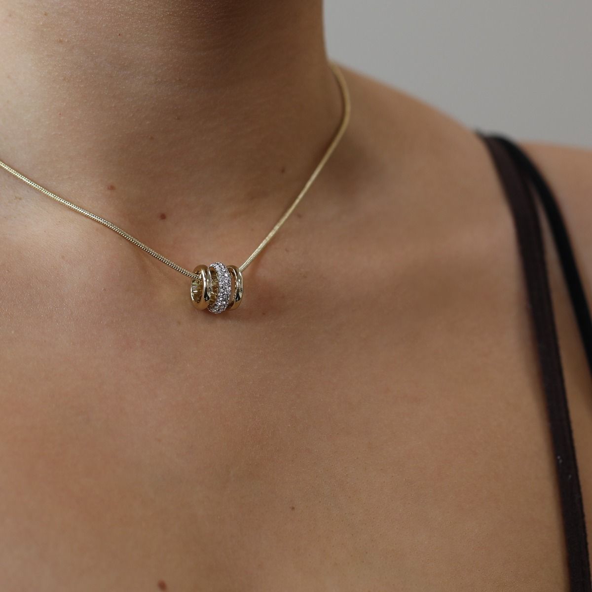 Simple and chic, the Aspire pendant is the perfect accessory for any outfit. Suspended from a sleek gold plated snake chain, the pendant features shimmering pave set crystals set into rhodium plating, wrapped between two bands of polished gold plate. Wear