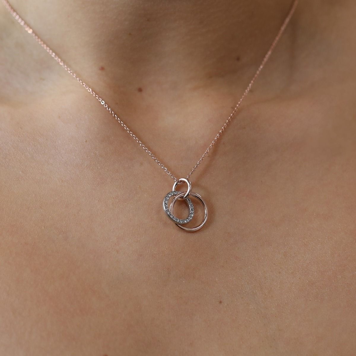 This crystal and polished two-tone pendant encapsulates sophistication with its classic design and modern twist. It effortlessly pairs together rhodium and rose gold hoops, which are finished off with crystals. 