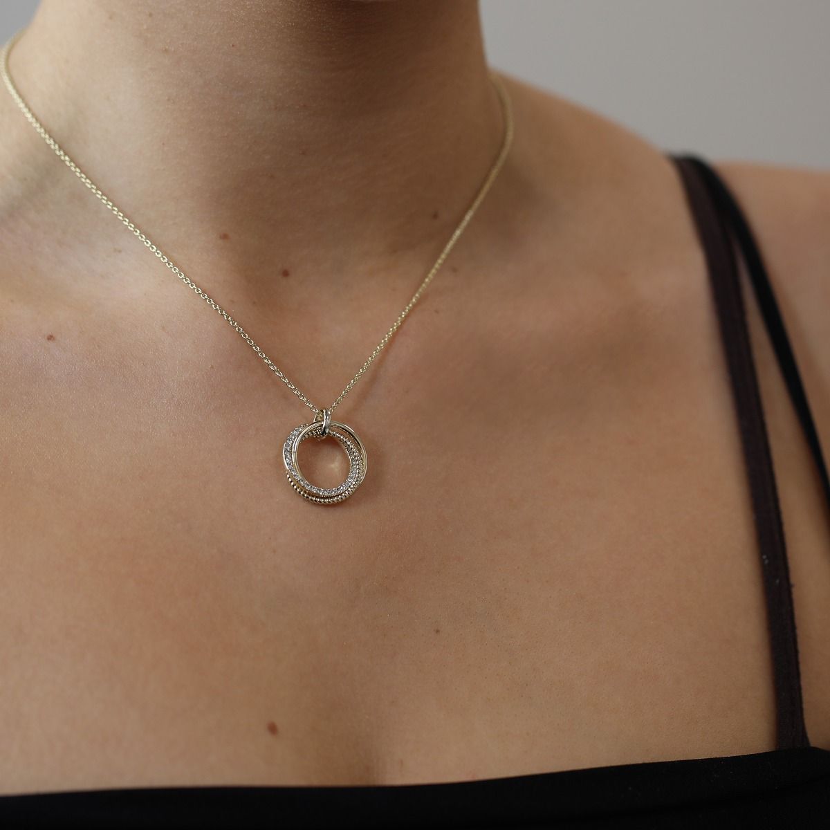 The polished trio hoop pendant presents a contemporary flair with its plain, textured and crystal hoops. Not only does this pendant experiment with texture, but it adds visual appeal. 