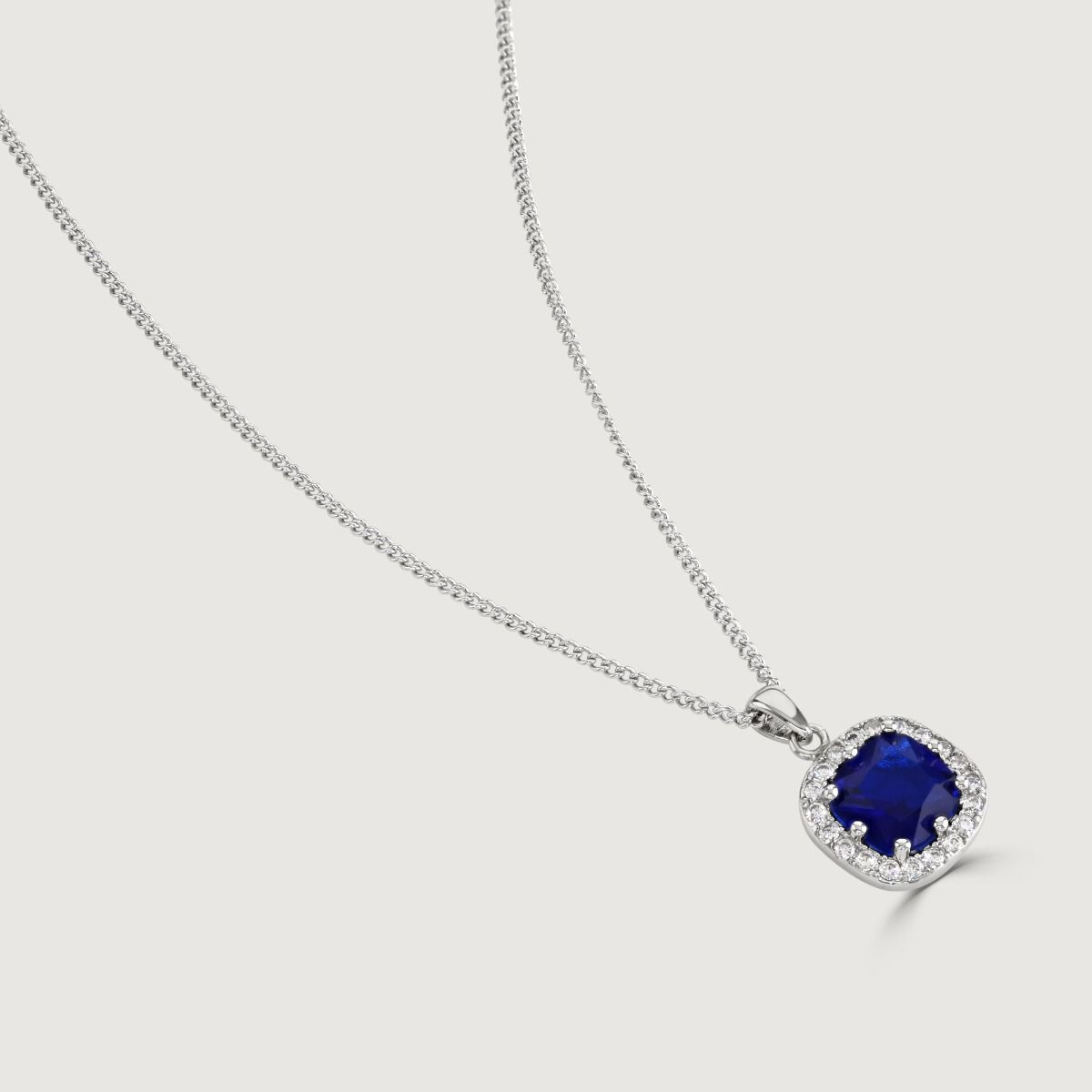 Reveal the allure of our Sapphire Cushion Halo Pendant, adorned with meticulously crafted cubic zirconia stones encircling a radiant clear cushion-cut centre. Elevate your style effortlessly with this timeless piece.