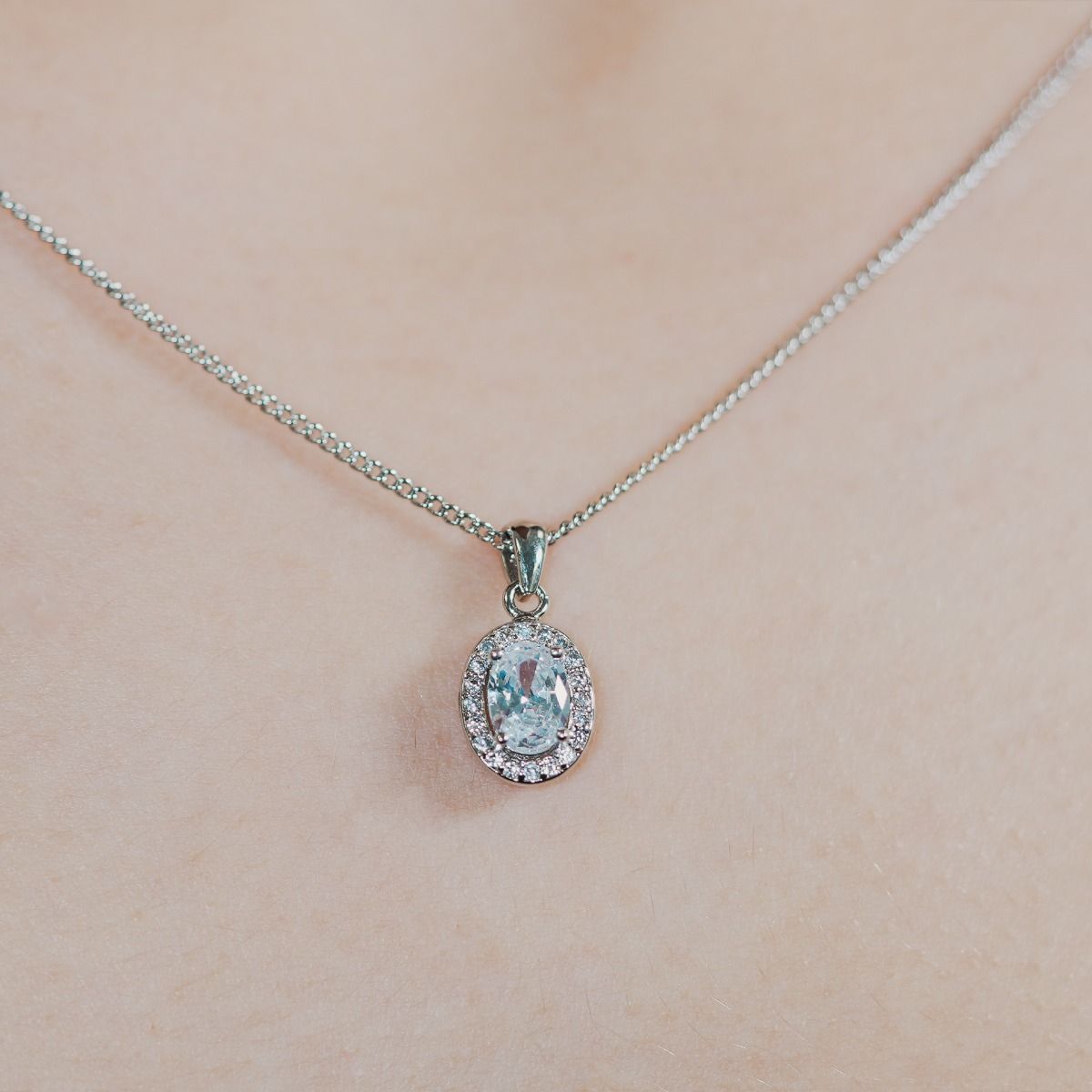Reveal the allure of our Clear Oval Halo Pendant, adorned with meticulously crafted cubic zirconia stones encircling a radiant clear oval-cut centre.