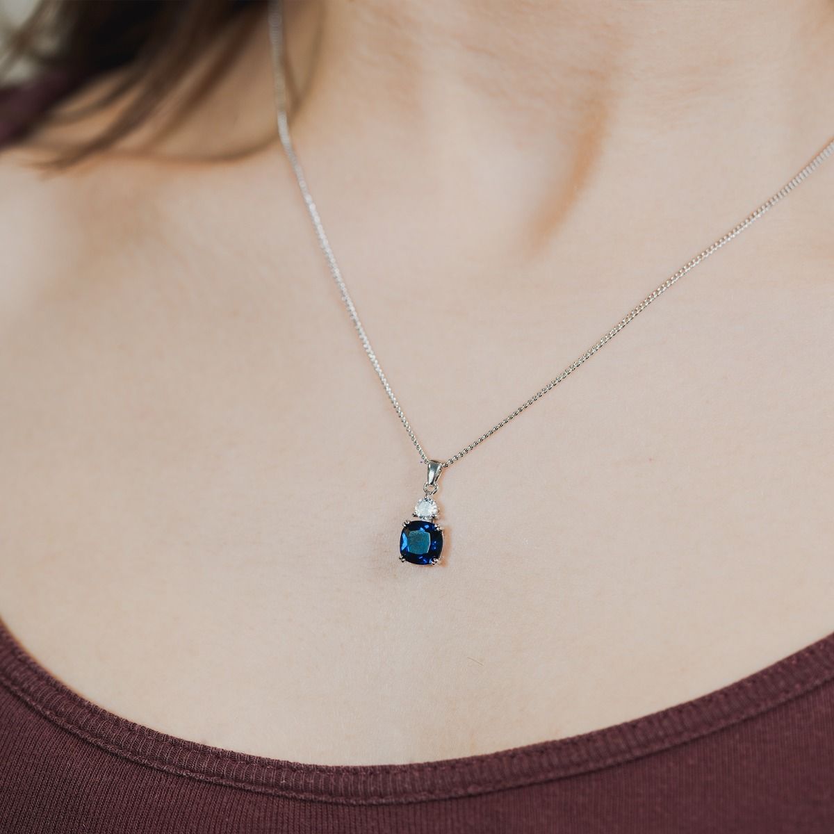 Discover the enchantment within our Sapphire Cushion Double Drop Pendant. A stunning halo of flawlessly cut cubic zirconia stones encircles an impressive cushion-cut centre stone in a captivating Sapphire hue. 