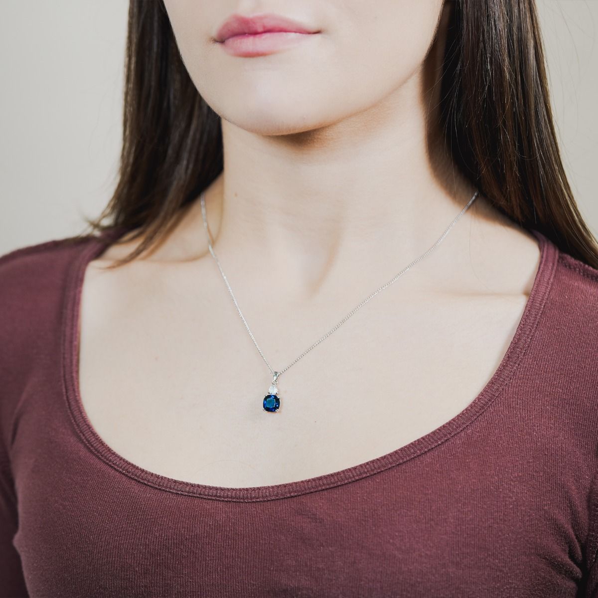 Discover the enchantment within our Sapphire Cushion Double Drop Pendant. A stunning halo of flawlessly cut cubic zirconia stones encircles an impressive cushion-cut centre stone in a captivating Sapphire hue. 