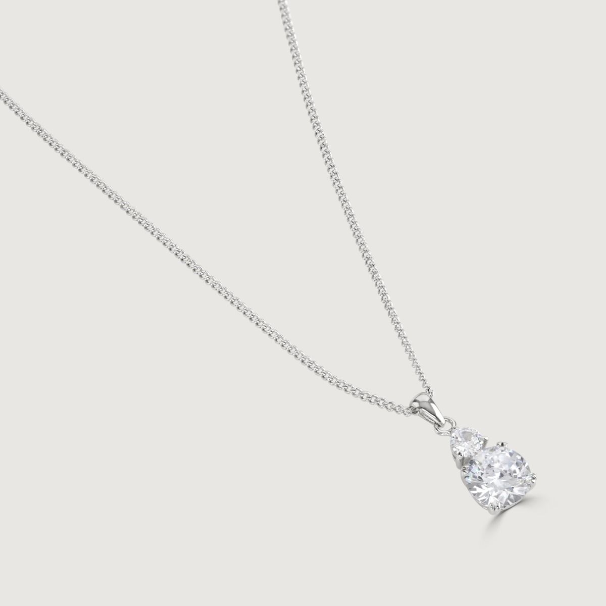 Unveil enchantment with our Clear Round Double Drop Pendant. A stunning halo of flawlessly cut cubic zirconia stones encircles an impressive cushion-cut centre stone, radiating a captivating allure. 
