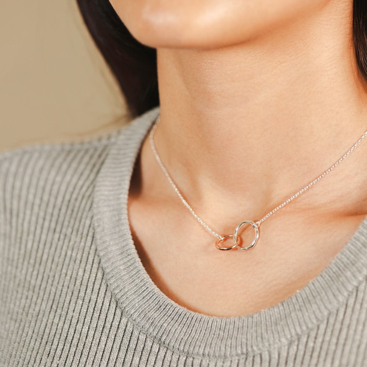 This beautifully delicate pendant features two free flowing rings entwined together and suspended on a silver-plated chain. The rose gold tone and silver-plated rings are complimented with a matching pair of stud earrings.
